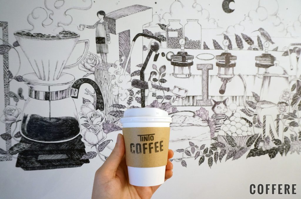 TINTO COFFEEのテイクアウトカップと壁の絵