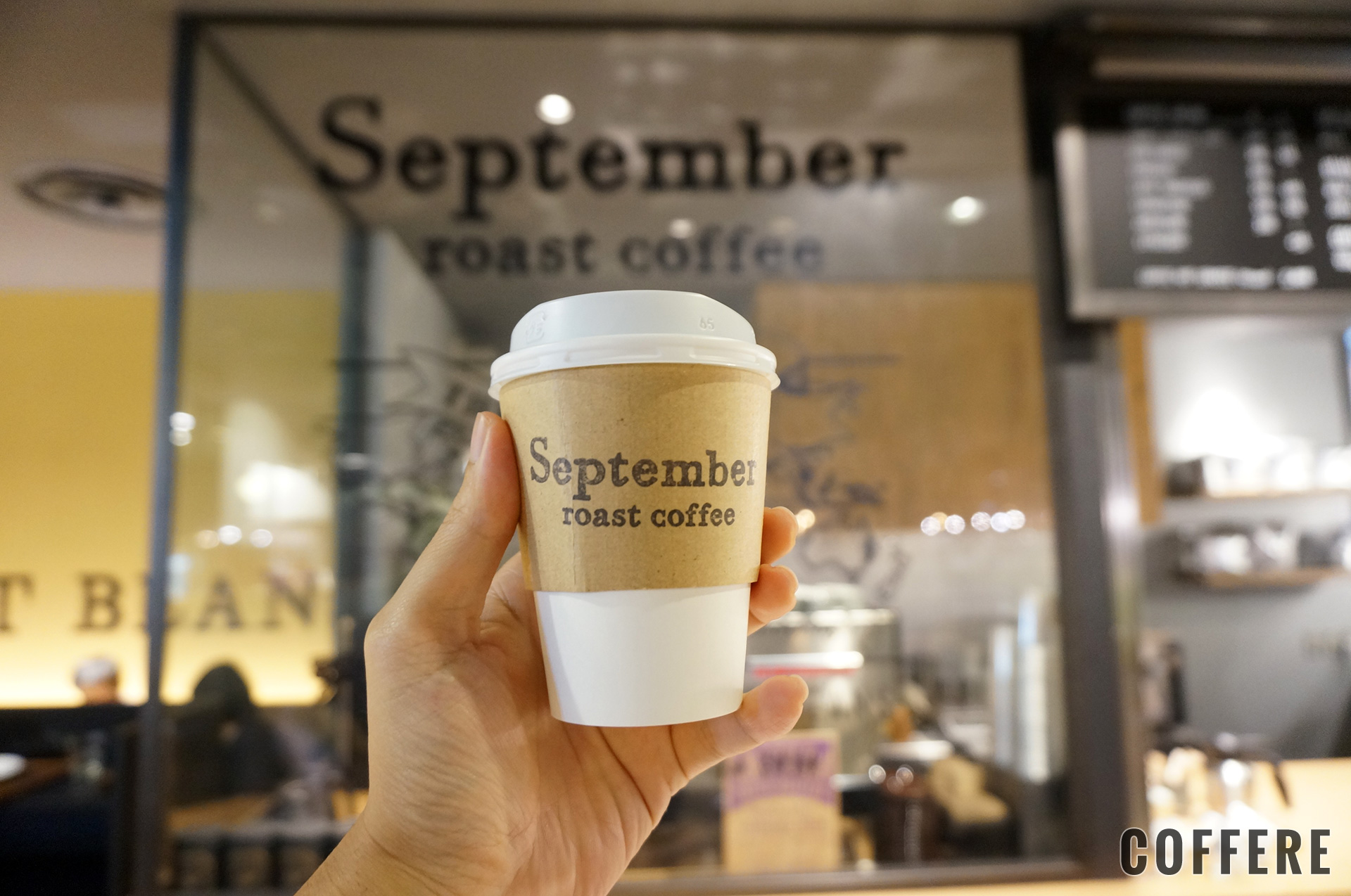 September roast coffeeのテイクアウトカップ。ロゴの前で